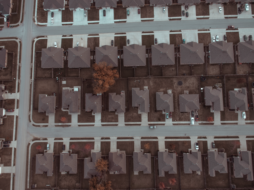 Top view image of a suburban neighborhood with houses, roads, and driveways.
