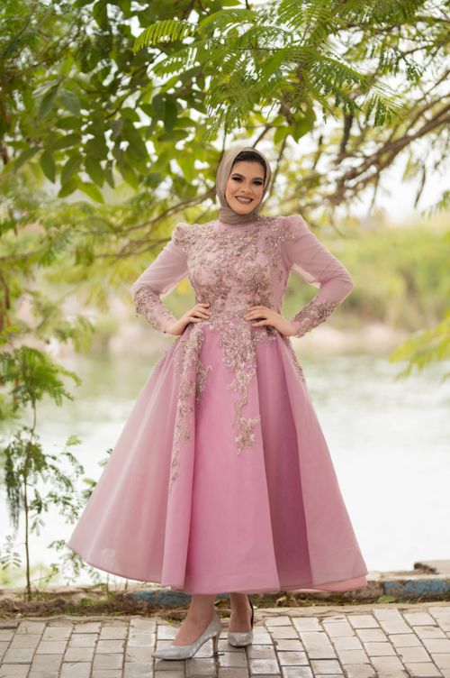 Free A woman in a beautiful pink dress and hijab posing in a lush outdoor setting. Stock Photo