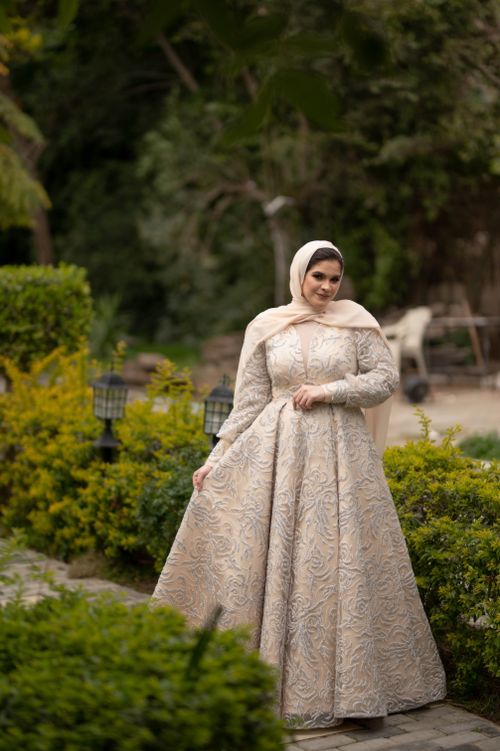 Free A woman in a white dress and hijab poses gracefully in a vibrant garden setting. Stock Photo
