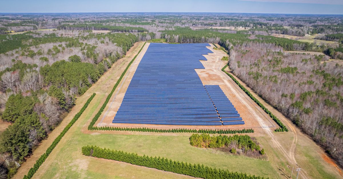 Aerial shot of a solar farm in a forested area near Louisburg, NC, showcasing renewable energy.
