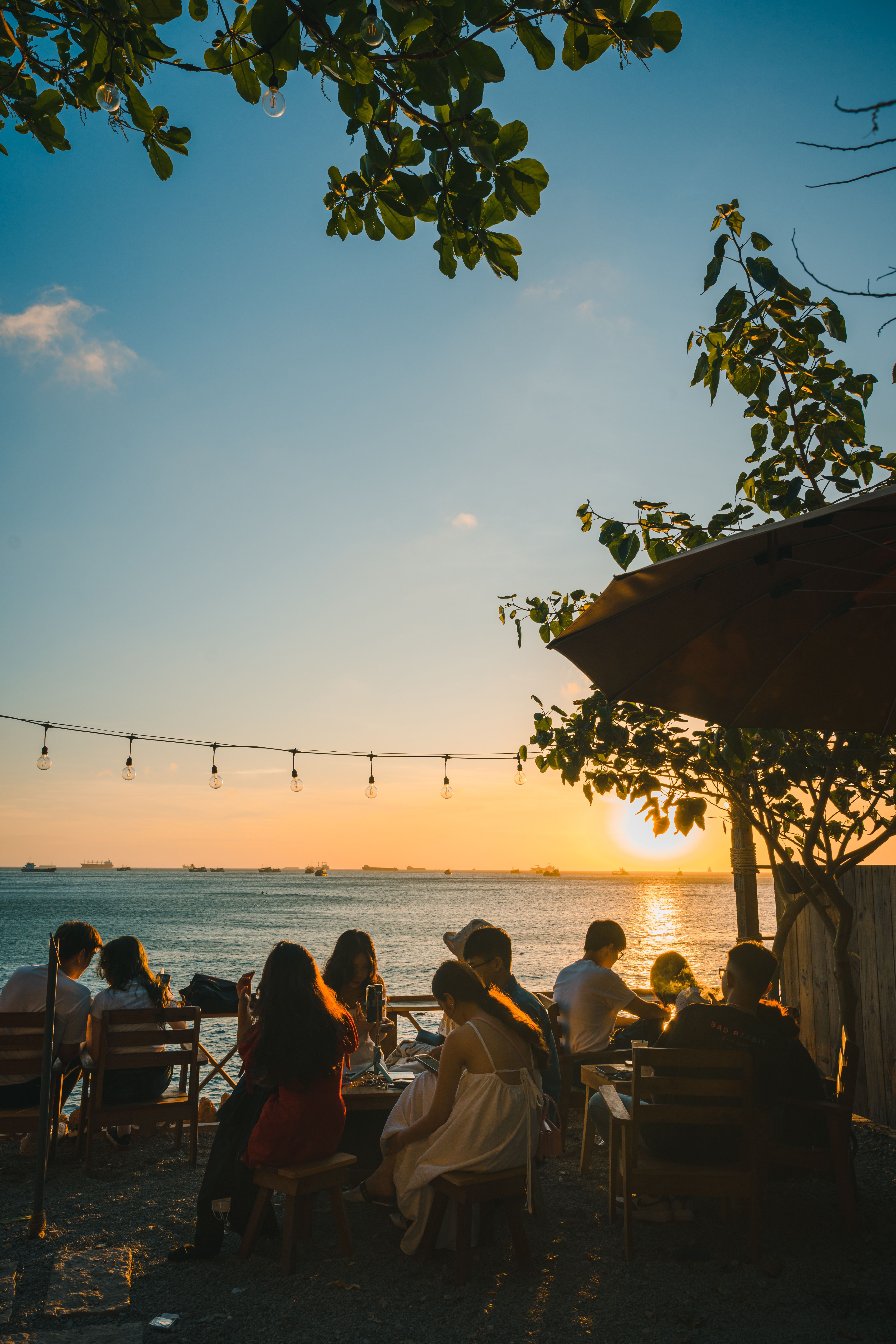 People enjoy a serene beachside setting during a beautiful sunset, with warm and inviting atmosphere.