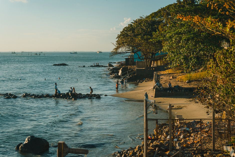 A tranquil beach scene with people enjoying the shoreline under a clear blue sky.