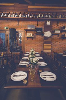 A rustic restaurant table setting with flowers, elegant glassware, and warm ambiance.
