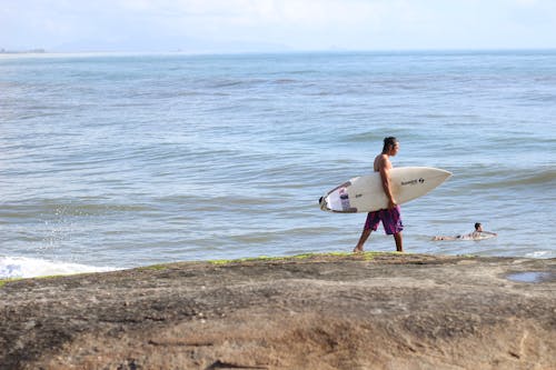 Man Walking on the Beach with a Surfboard 