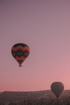 Stunning hot air balloons floating over Cappadocia's landscape during sunrise.