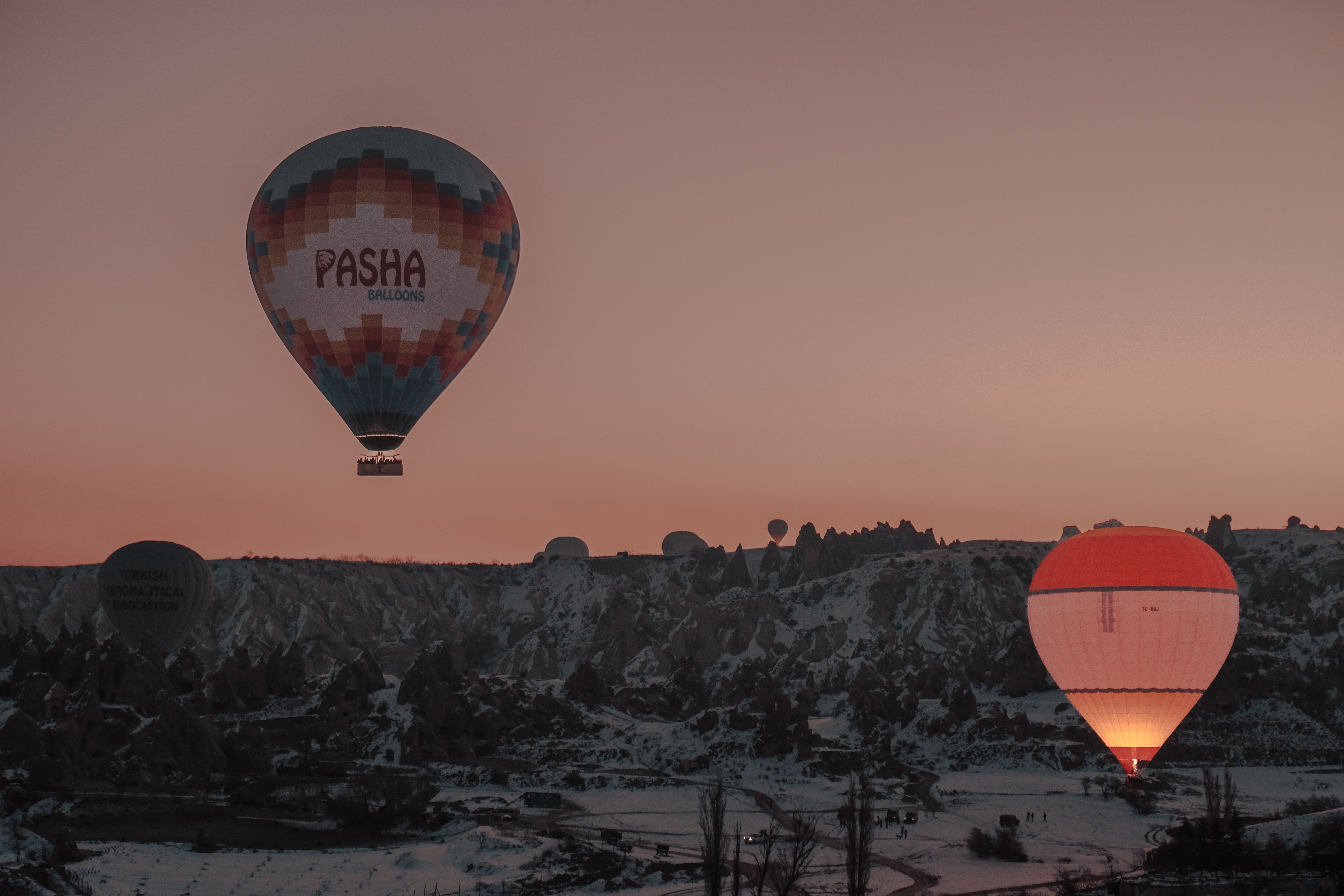 Capturing the serene hot air balloons over Cappadocia's snow-dusted landscape at sunrise.