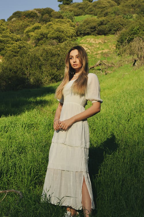 Young Woman in a Dress Posing on a Grass Field 