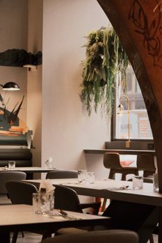 Elegant modern restaurant interior featuring stylish furniture and lush green plant decor.