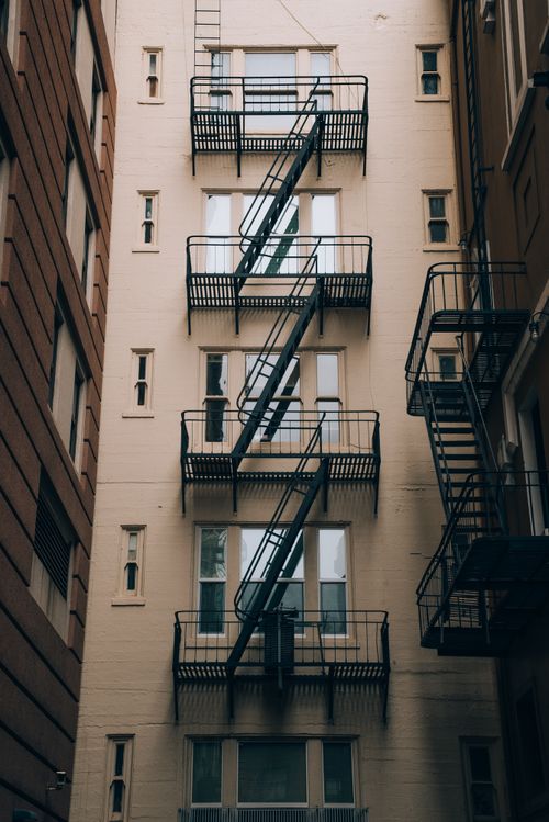 Free Low angle view of an urban building with classic fire escape stairs in an alleyway. Stock Photo