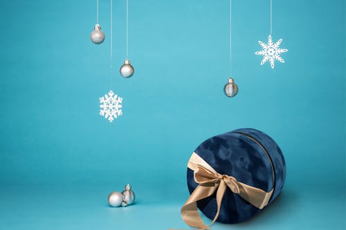 Gift ribbon box. White gift box with cyan ribbon, New Year balls and winter tree in Christmas composition on dark blue background for greeting card. Christmas, winter, new year concept