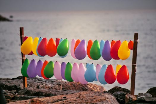 Vibrant balloons strung along a seaside view during sunset, creating a colorful display.