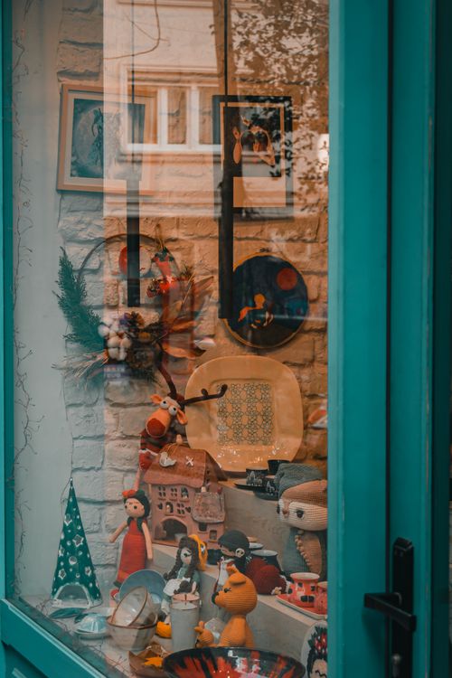 Free A charming Christmas-themed window display featuring festive decorations, dolls, and holiday wreaths. Stock Photo