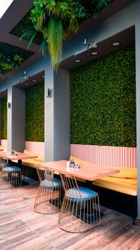 A trendy restaurant interior featuring modern furniture, vertical gardens, and ample dining space.
