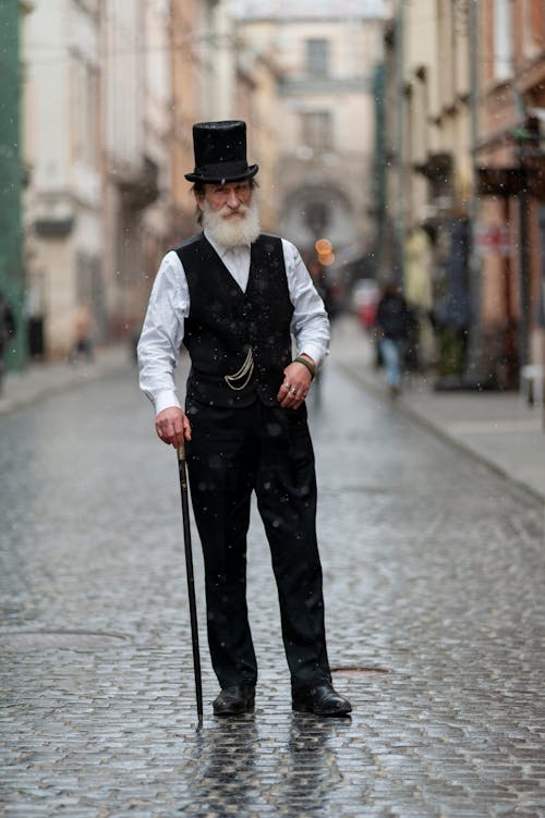 Man with a Walking Stick Standing on a Paving Street