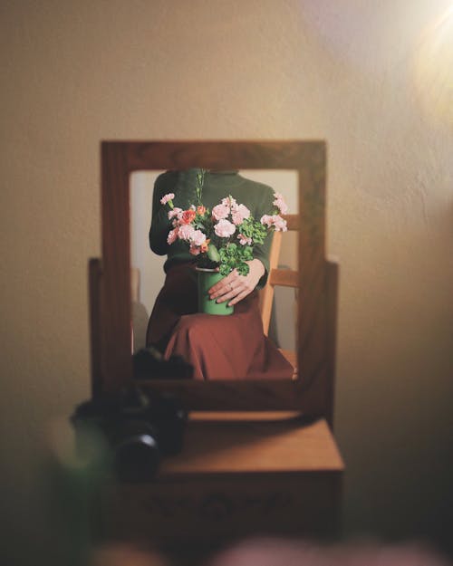 Mirror with the Reflection of a Bouquet in a Vase Hold on a Knee