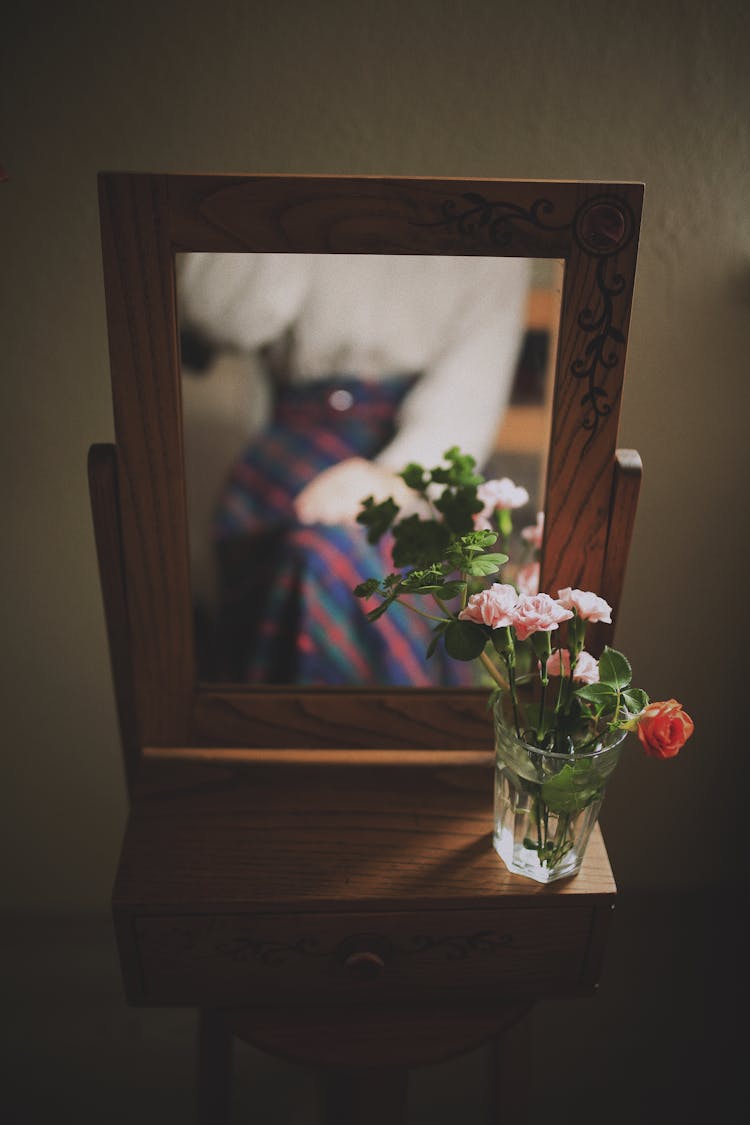 Roses In A Vase By A Mirror And A Reflection Of A Woman