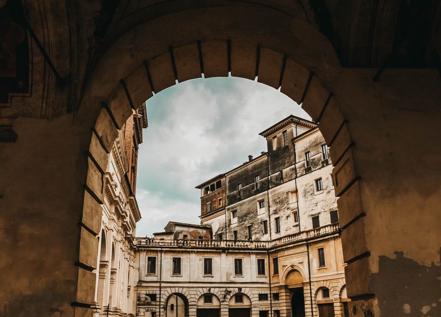 Capture of a historic building viewed through an ancient archway showcasing gothic architecture.