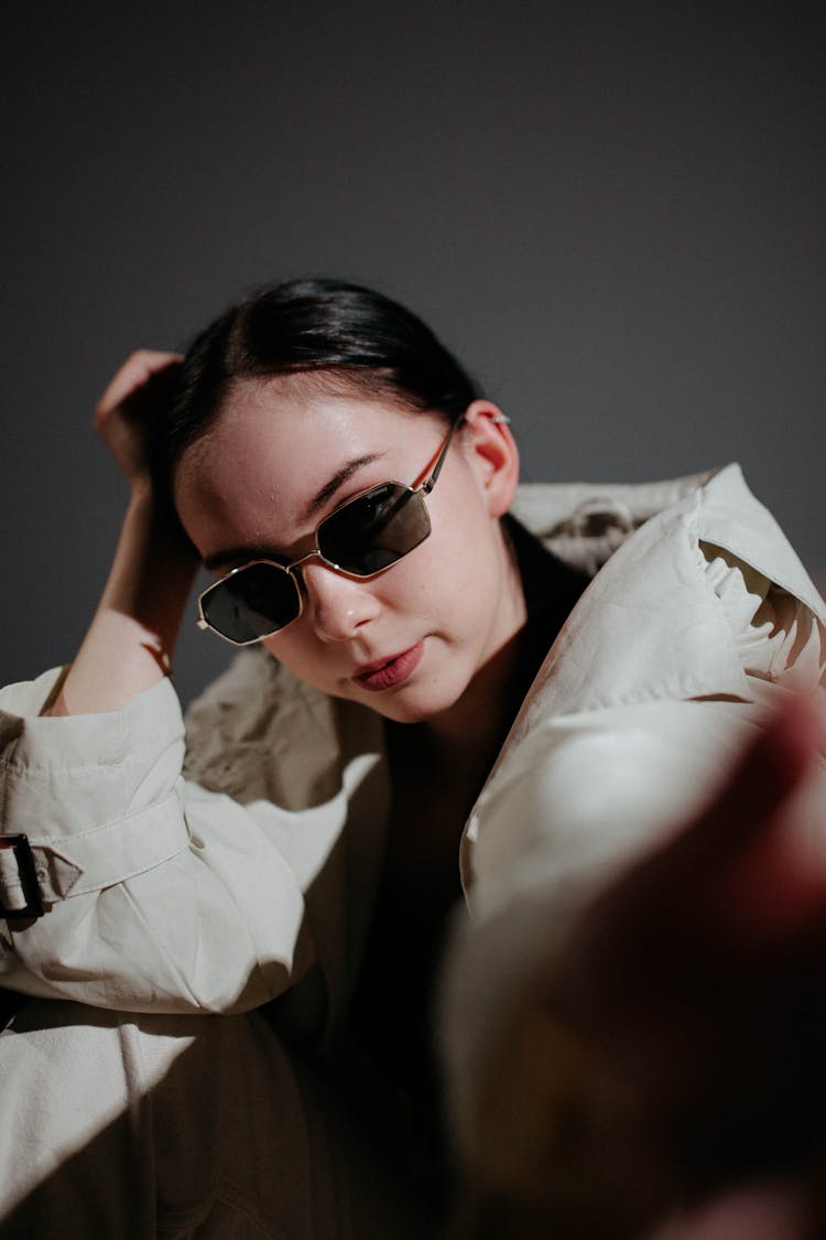 Woman In Trench Coat And Sunglasses Posing In Studio