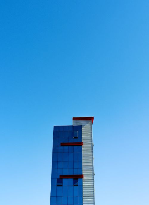Free A modern skyscraper with glass façade set against a clear blue sky in MG, Brazil. Stock Photo
