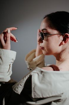 Trendy woman in sunglasses posing in a stylish coat, showcasing modern fashion.