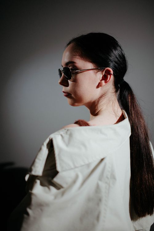 Free A fashionable woman poses in a studio wearing sunglasses and a stylish coat, showcasing modern elegance. Stock Photo