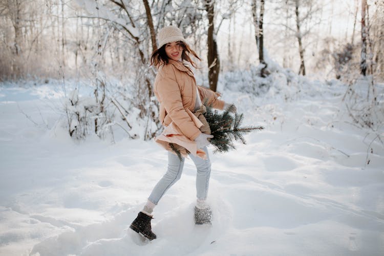 Woman With Spruce Branches Running In Snow In Forest