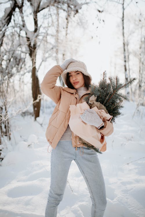 Woman in Jacket and with Evergreen Branches in Winter