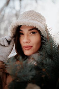 A woman in winter clothing poses warmly with a snowy background. Perfect for seasonal lifestyle themes.