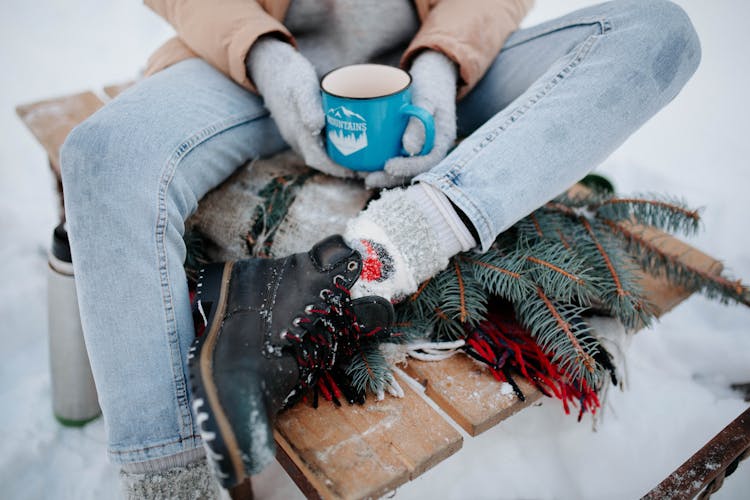 Woman Sitting On Sleight With Tea On Winter Day