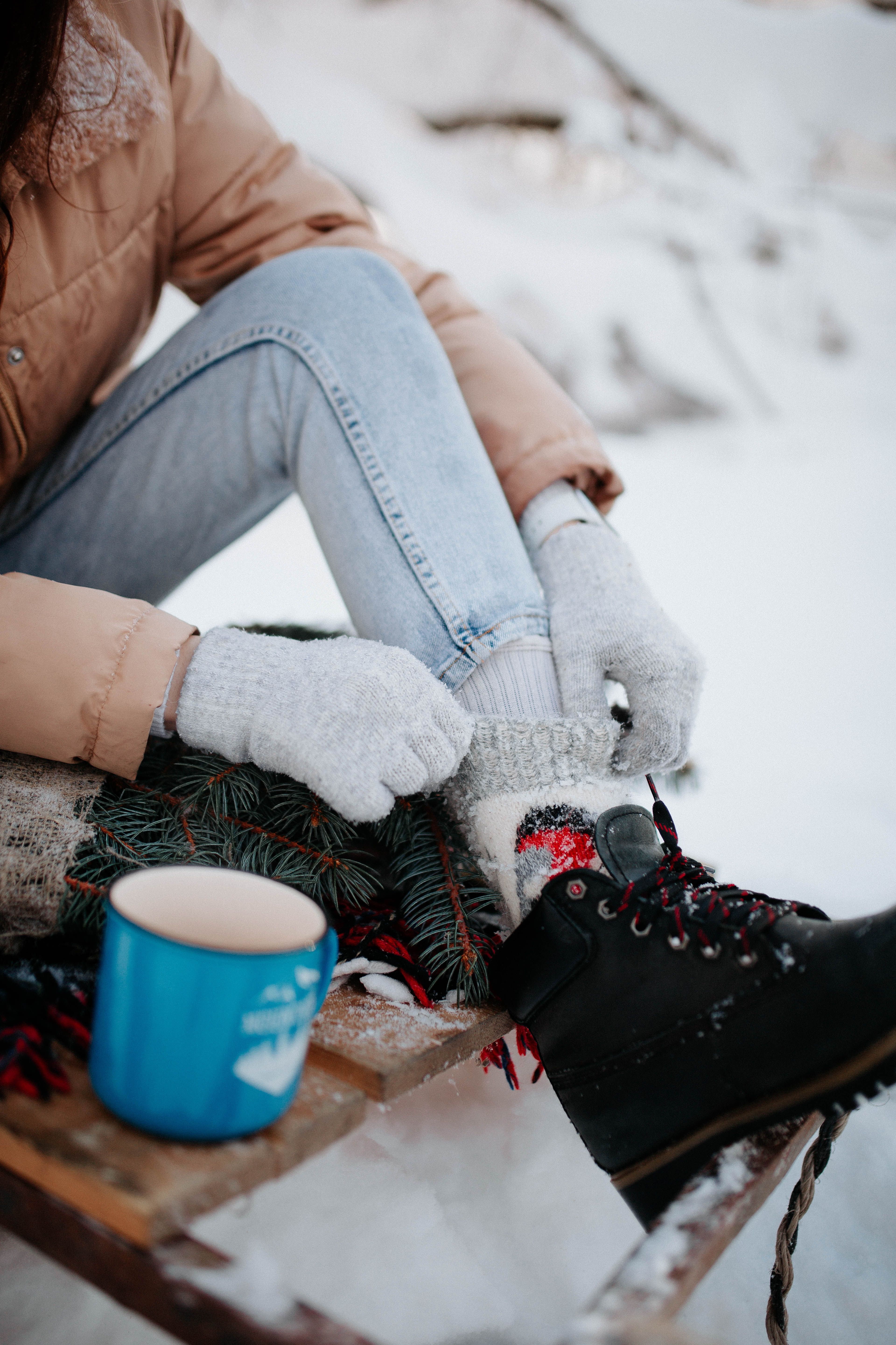 Woman putting on her boots in the snow