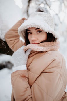 Fashionable woman in winter wear posing outdoors with a warm jacket and hat.