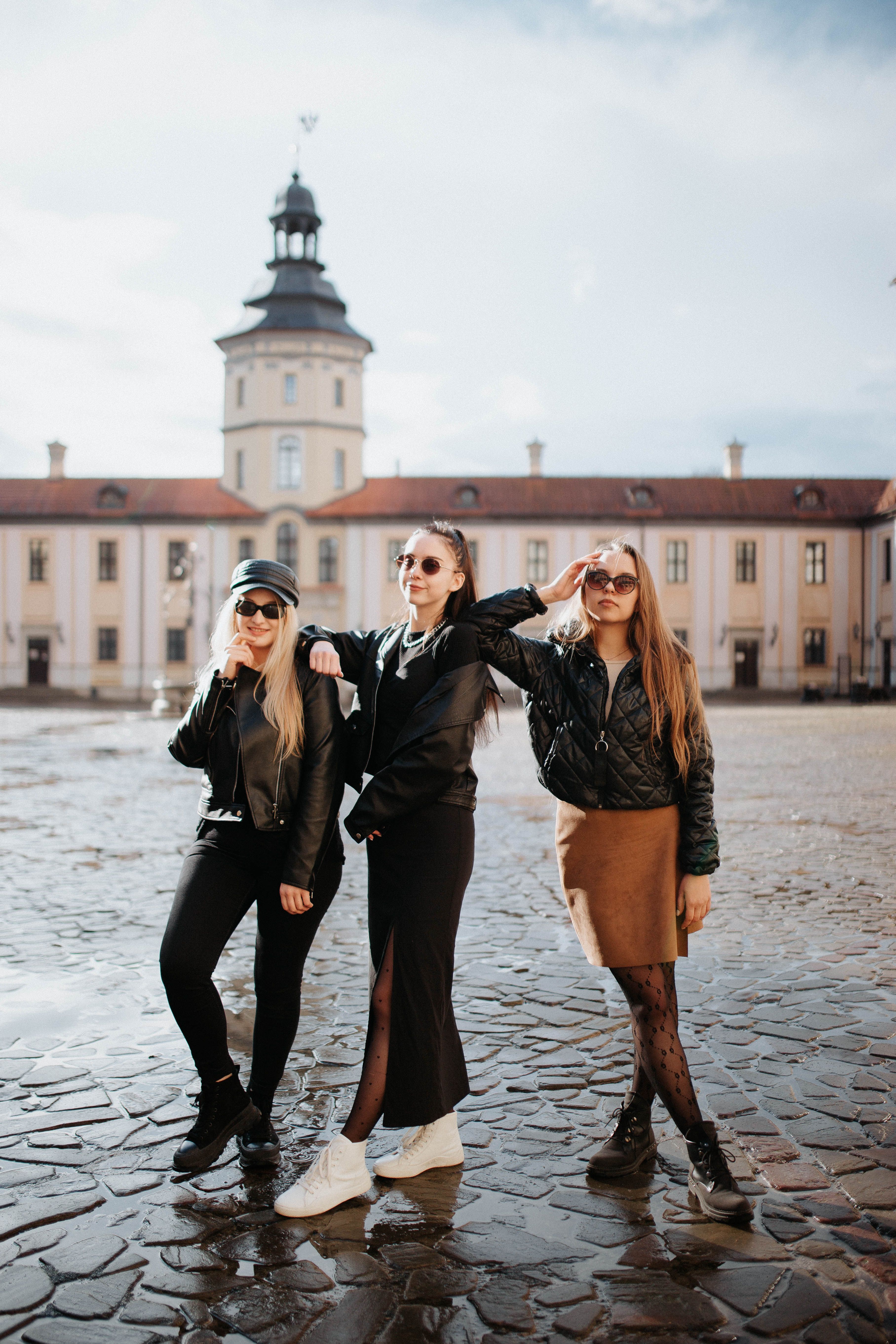Three Young Women Posing on a City Square with Tower in Background ...