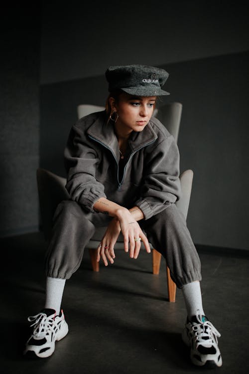 Woman Wearing a Khaki Fleece Tracksuit and a Hat Posing on an Armchair