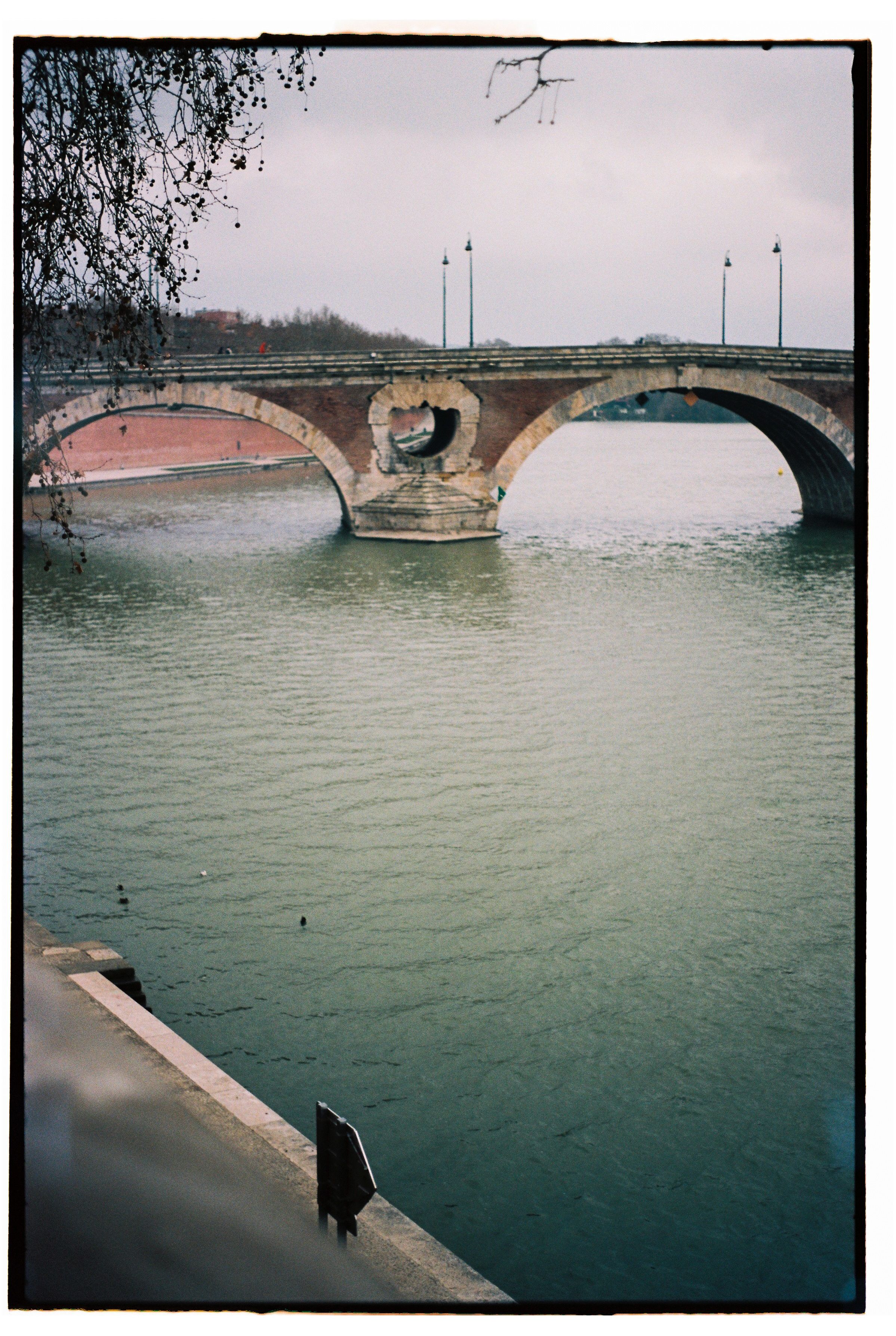 Captivating view of the Pont Neuf bridge over the Garonne River in Toulouse, captured in a classic film style.