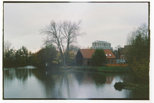 Serene autumn scene in Bruges, Belgium, showcasing a canal, trees, and quaint architecture.