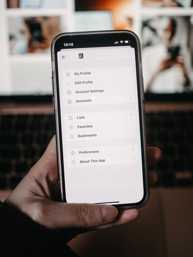 A person holding a smartphone showing the settings menu in front of a blurred background