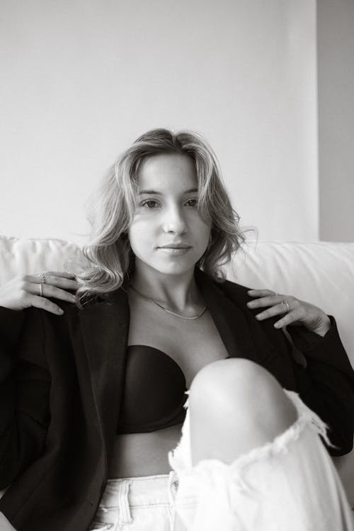 A woman in a black bra and jeans sitting on a couch