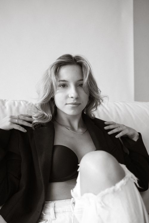 Free Chic black and white portrait of a woman relaxing indoors wearing a jacket. Stock Photo