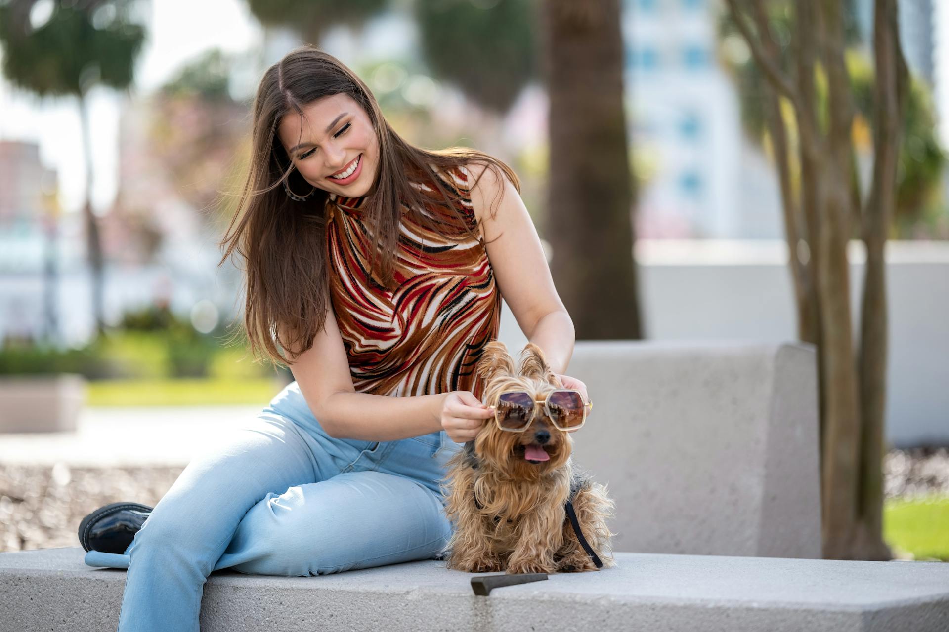 Laughing Woman Putting Sunglasses on her Dog