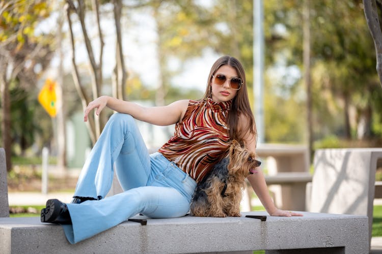 Woman In Sunglasses Posing On A Bench With Her Pet Dog