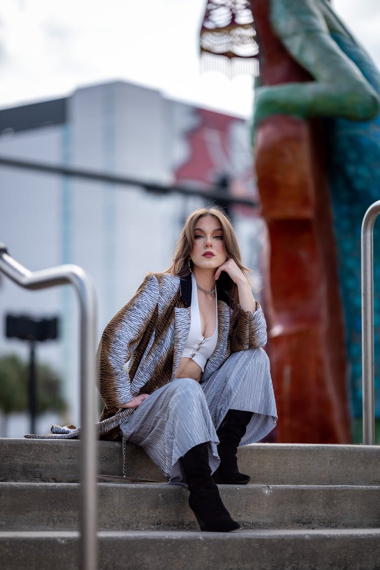 Woman In A Coat And Boots Sitting On A Staircase