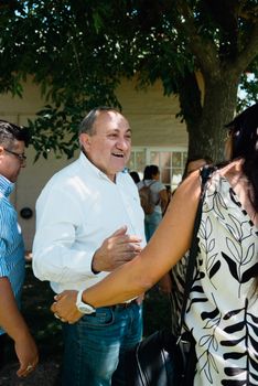 A cheerful outdoor meeting with people interacting and smiling under a tree.