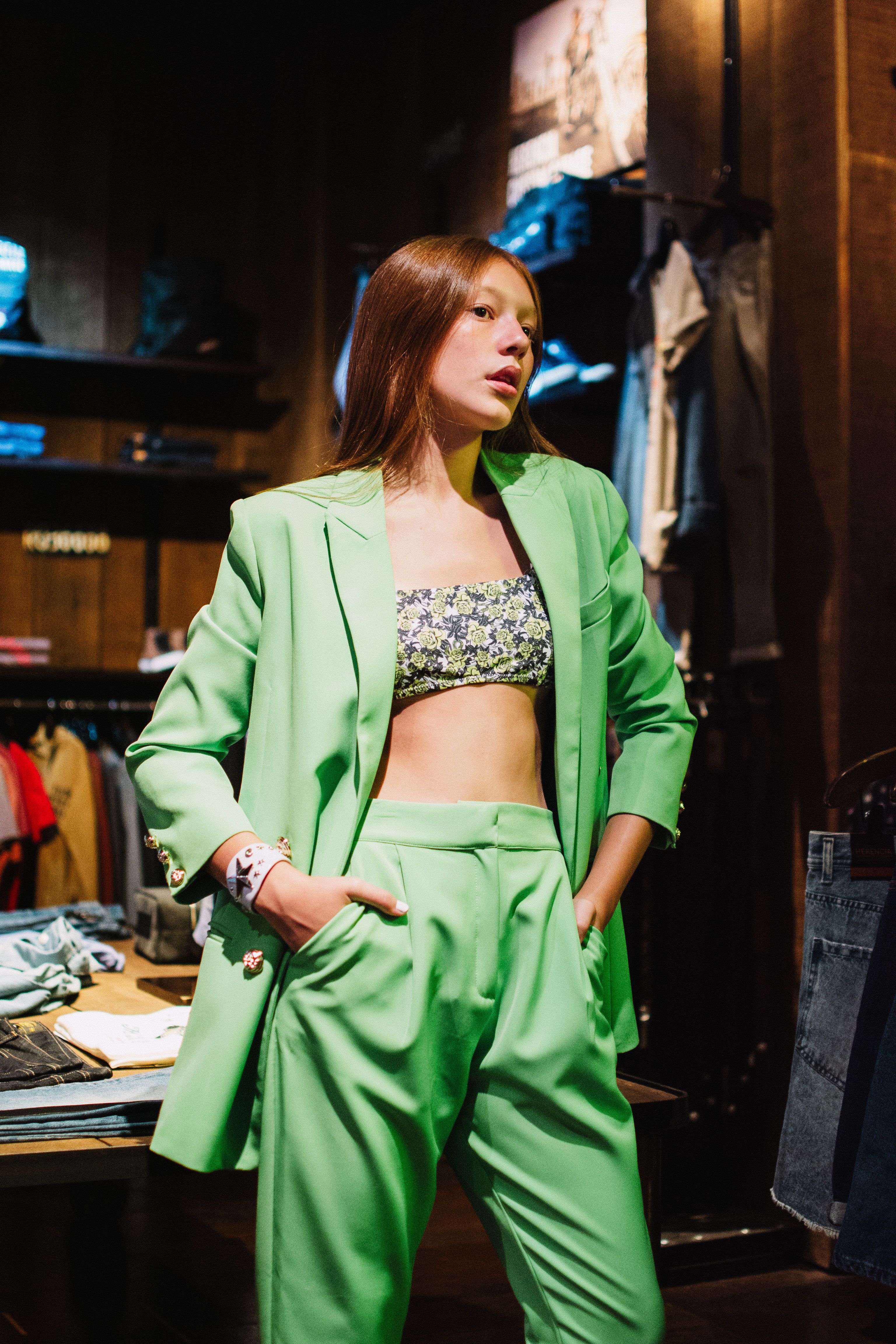 Modelo de moda posando em um vibrante terno verde em um ambiente de boutique elegante.