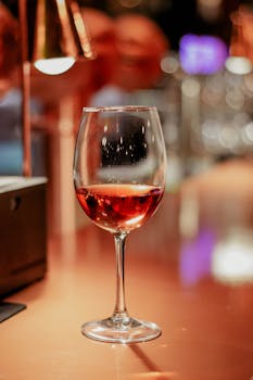 Close-up of an elegant wineglass filled with red wine on a stylish bar counter.