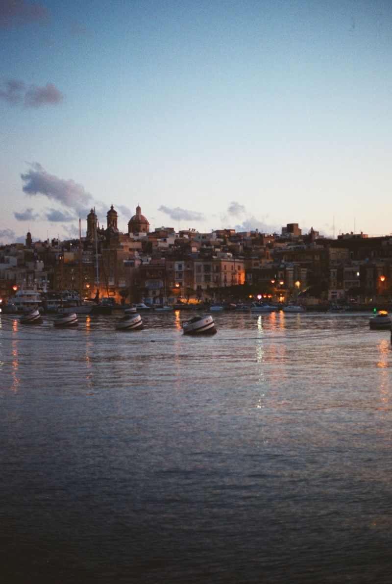 Boats reflected in calm water at sunset in a Maltese harbour