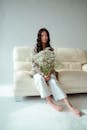 一位年轻女子手捧一束鲜花，优雅地坐在米色沙发上