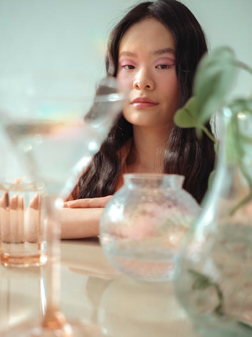 A woman with long hair sitting at a table with a vase