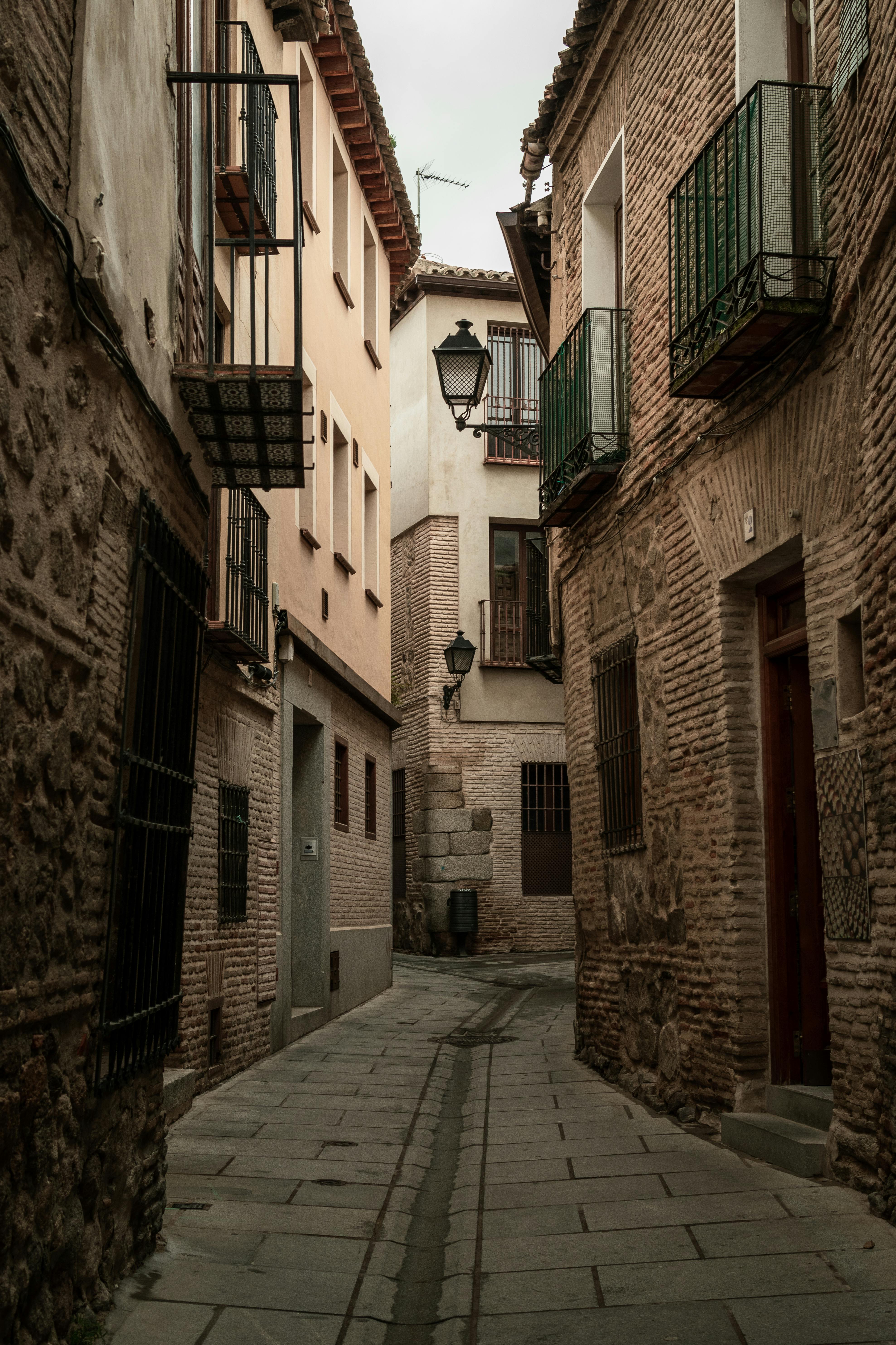 Explore a narrow passage in a historic old town with rustic residential buildings and urban charm.
