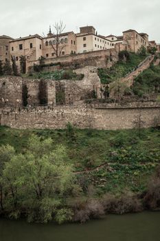 Ancient stone fortifications and buildings on a hill in an urban area, showcasing medieval architecture.