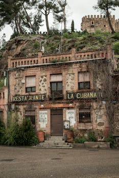 Vintage facade of Restaurante La Cubana with castle ruins in the background.